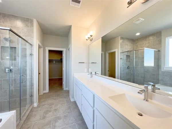 a spacious bathroom with a double vanity sink mirror and shower