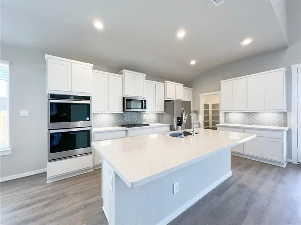 a kitchen with stainless steel appliances a stove a sink and white cabinets