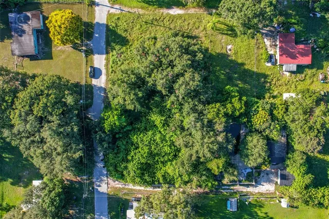 an aerial view of residential house with outdoor space and trees all around