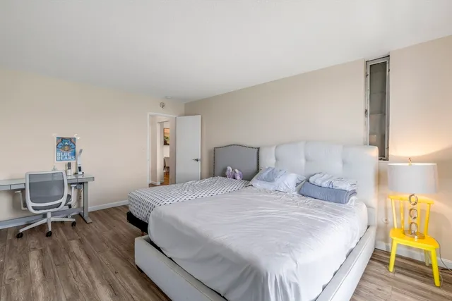 a spacious bedroom with a bed and wooden floor