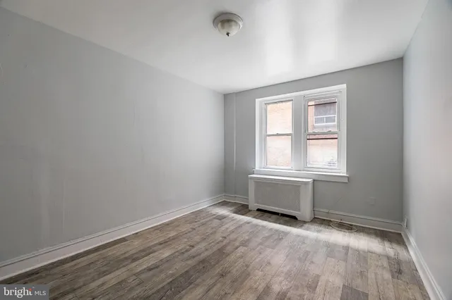 a view of an empty room with wooden floor and closet