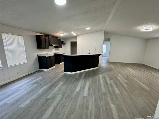 a view of kitchen with stainless steel appliances kitchen island a sink dishwasher a refrigerator and a microwave oven on granite countertops with wooden floor