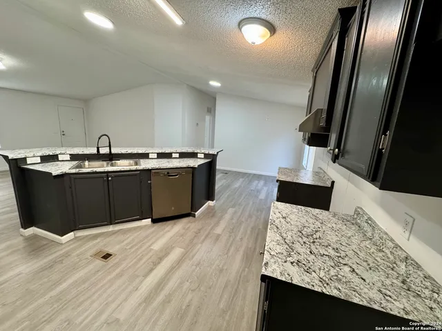 a kitchen with stainless steel appliances granite countertop a sink stove and wooden floor