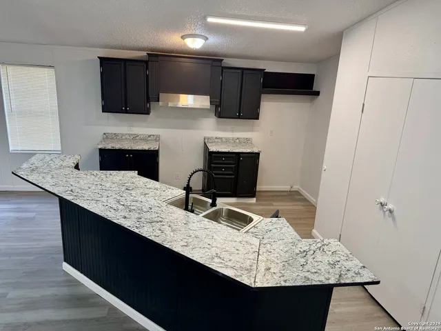 a kitchen with granite countertop a sink and a stove top oven with wooden floor