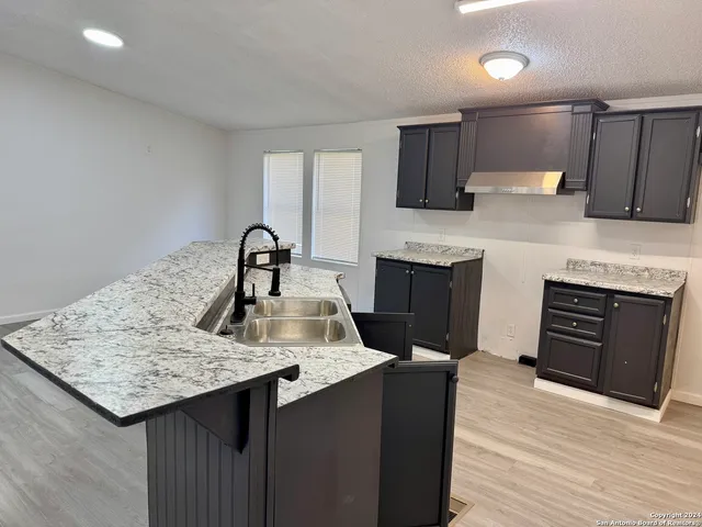 a kitchen with granite countertop a stove top oven sink and cabinets