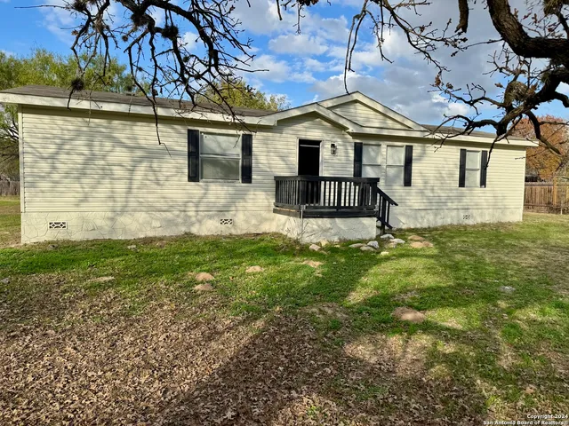 a white house with a small yard and large trees