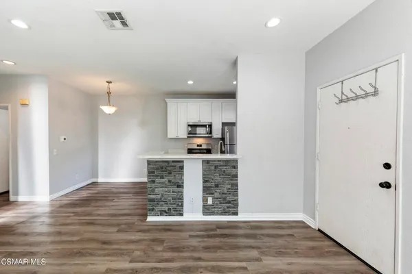 a view of kitchen with granite countertop cabinets and refrigerator