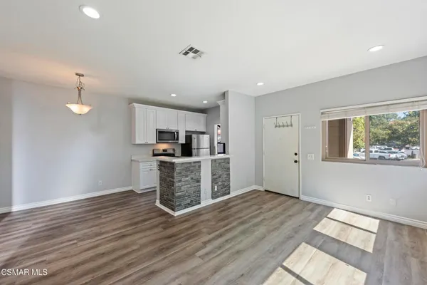 a kitchen with stainless steel appliances kitchen island granite countertop a refrigerator and a stove top oven