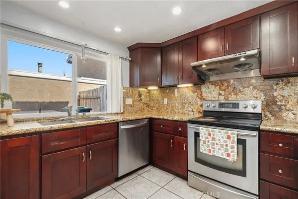 a kitchen with stainless steel appliances granite countertop wooden cabinets stove top oven and sink