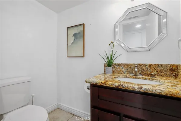 a bathroom with a granite countertop toilet sink and mirror