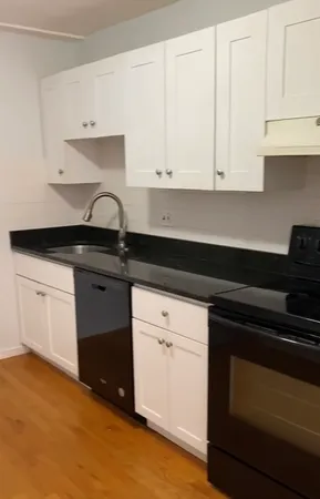a kitchen with granite countertop white cabinets and black appliances
