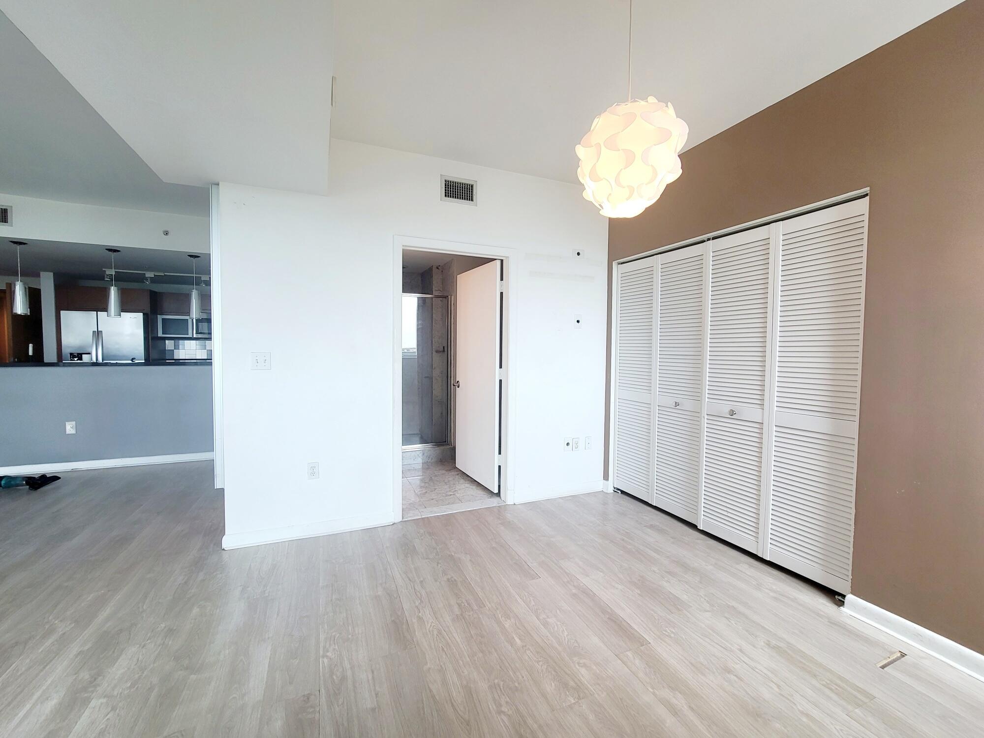 244 Biscayne Boulevard, Unit 401 Miami, FL 33132 - Photo 15 of 36 an empty room with wooden floor and chandelier