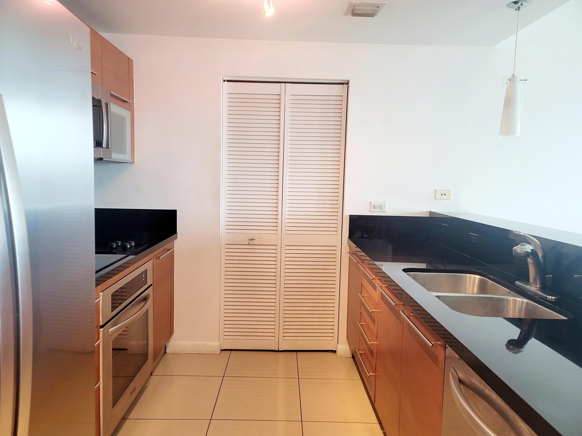 244 Biscayne Boulevard, Unit 401 Miami, FL 33132 - Photo 10 of 36 a kitchen with granite countertop a sink and a stove top oven