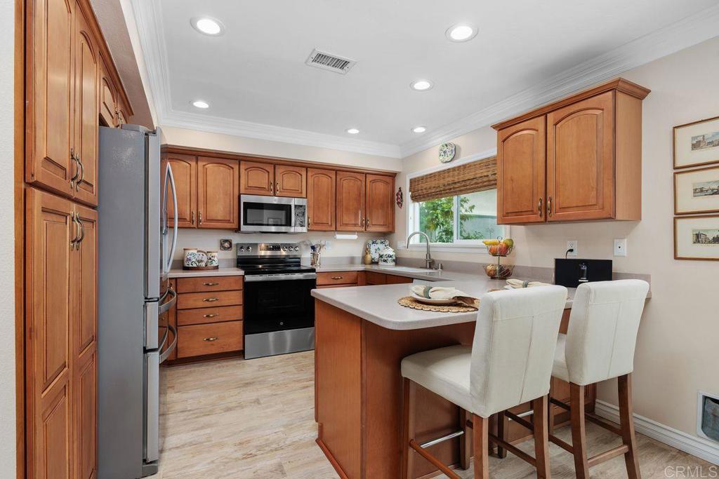 3709 Sesame Way Oceanside, CA 92057 - Photo 15 of 39 a kitchen with stainless steel appliances granite countertop a stove top oven a sink dishwasher a dining table and chairs with wooden floor