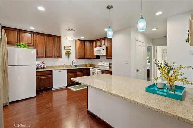 a kitchen with granite countertop a refrigerator a stove a sink and a oven with wooden floor