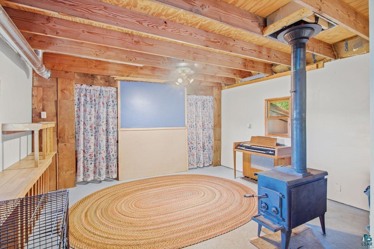 65889 Old County Road Marengo, WI 54855 - Photo 25 of 44 Exposed wood beam ceiling with wood support posts and a built-in wood-burning stove