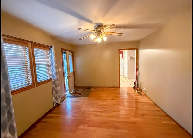 a view of an empty room with window and wooden floor
