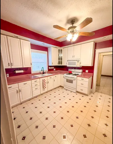 a kitchen with granite countertop a white stove top oven and refrigerator