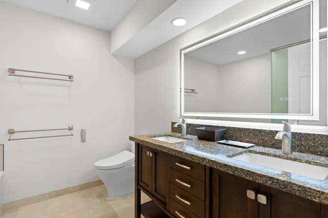 a bathroom with a granite countertop sink a toilet and a mirror