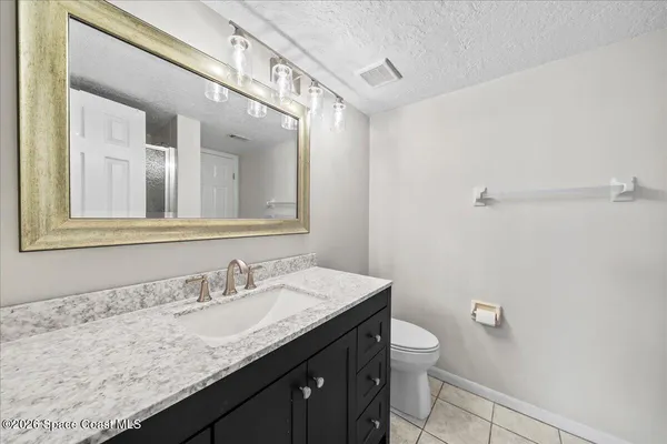 a bathroom with a granite countertop sink a toilet and a mirror