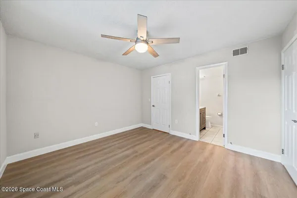 an empty room with wooden floor ceiling fan and windows
