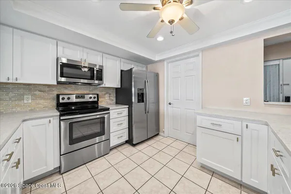 a kitchen with white cabinets stainless steel appliances and a window
