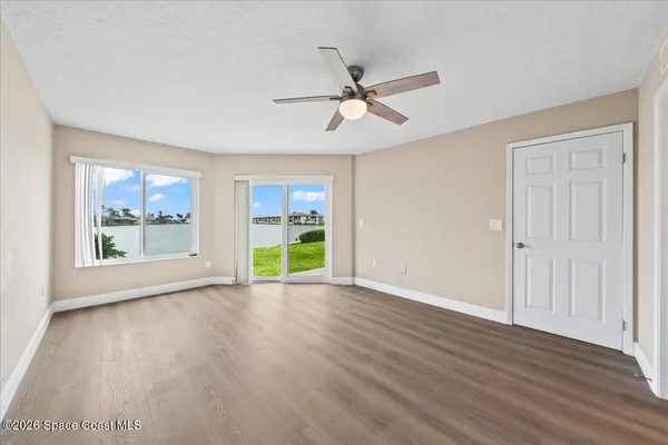 a view of an empty room with a window and wooden floor