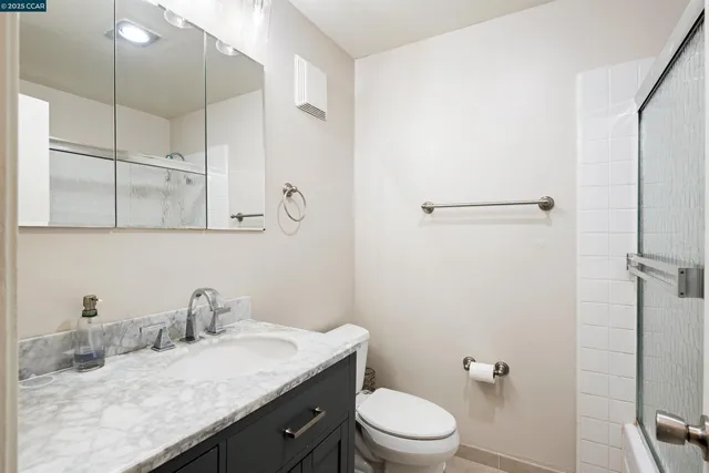 a bathroom with a granite countertop sink a toilet and shower