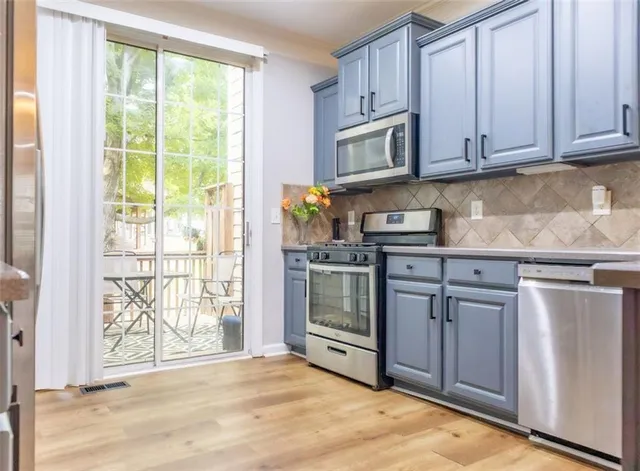 a kitchen with stainless steel appliances granite countertop a sink and cabinets with wooden floor