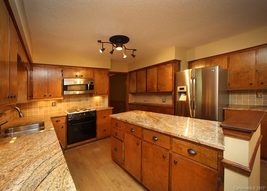 124 Friendfield Drive, Unit 10 Fort Mill, SC 29715 - Photo 7 of 24 a large kitchen with stainless steel appliances kitchen island granite countertop a refrigerator a stove and a sink with wooden floor