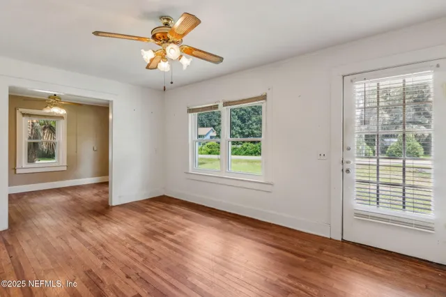 a view of an empty room with window and wooden floor