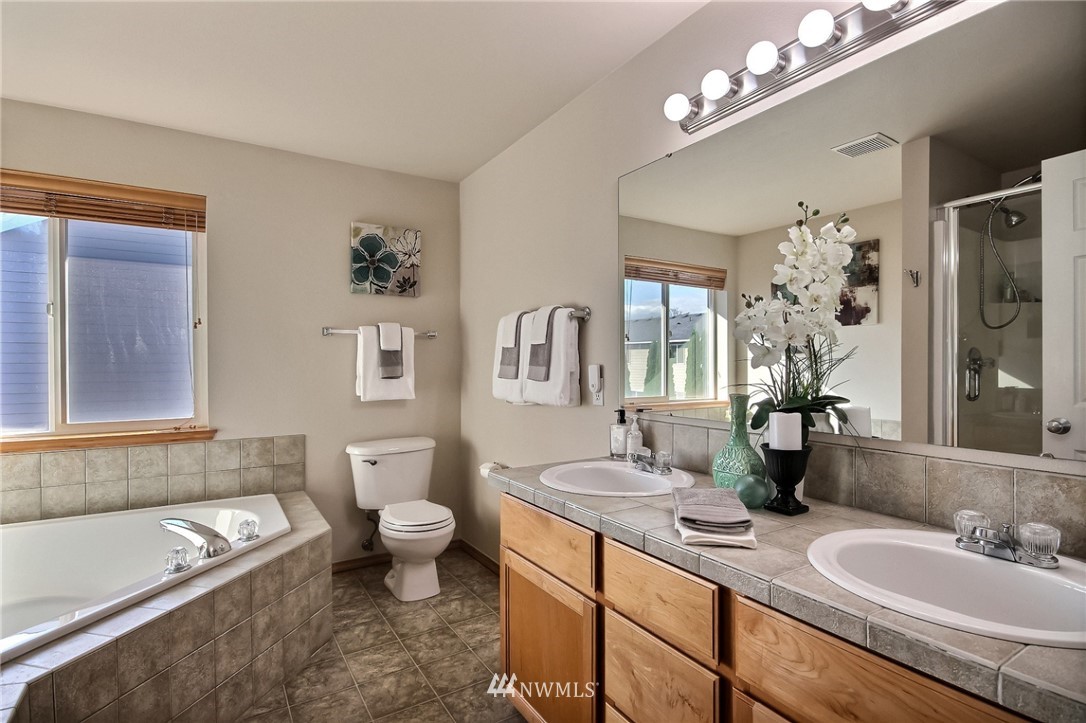 5217 Northeast 11th Street Renton, WA 98059 - Photo 16 of 25 a bathroom with a granite countertop sink a toilet a mirror and shower