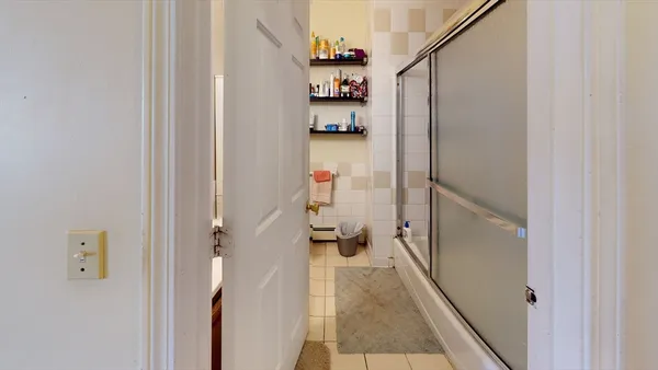 a view of a hallway with wooden floor and a bathroom