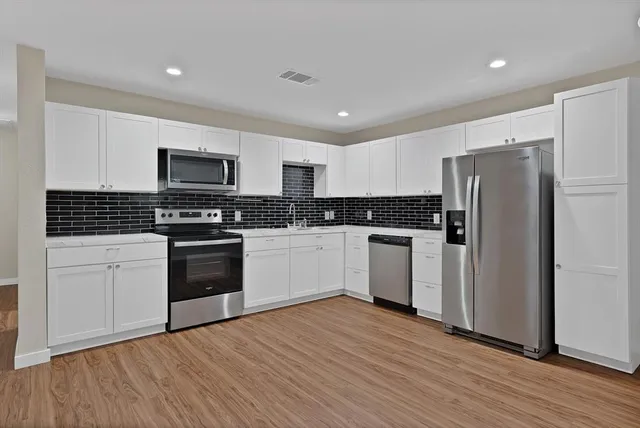 a kitchen with granite countertop white cabinets and stainless steel appliances