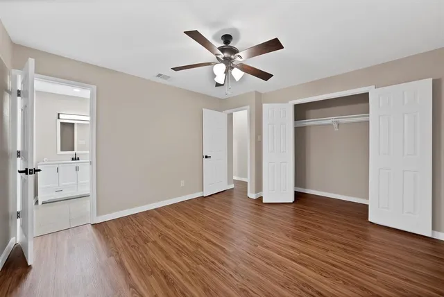 an empty room with wooden floor a ceiling fan and windows