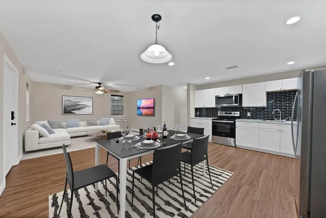 a kitchen with stainless steel appliances kitchen island granite countertop a stove a sink dishwasher a dining table and chairs with wooden floor
