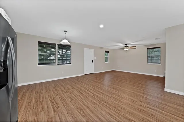 an empty room with wooden floor chandelier and windows