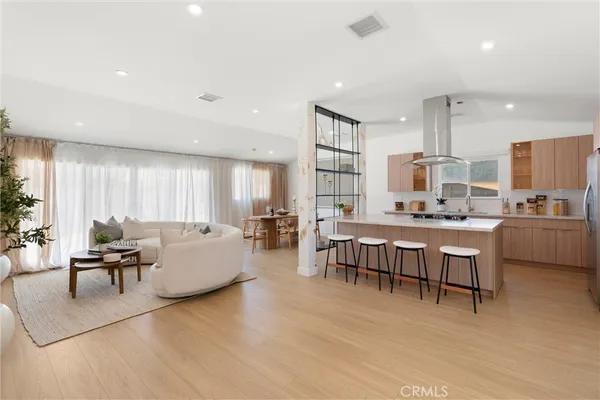 a living room with furniture kitchen view and a wooden floor