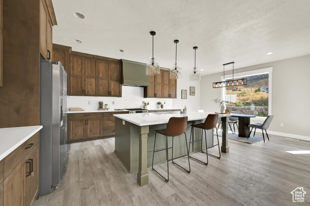 658 West 500 South Logan, UT 84321 - Photo 8 of 25 Kitchen featuring a center island with sink, pendant lighting, a kitchen breakfast bar, decorative backsplash, and light wood finished floors
