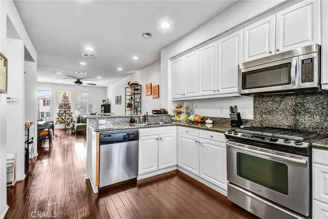 a kitchen with stainless steel appliances granite countertop a stove top oven a sink a counter space and cabinets