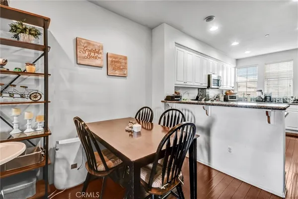 a kitchen with stainless steel appliances kitchen island granite countertop a dining table chairs and a refrigerator