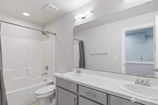 a bathroom with a sink double vanity granite tub and a mirror