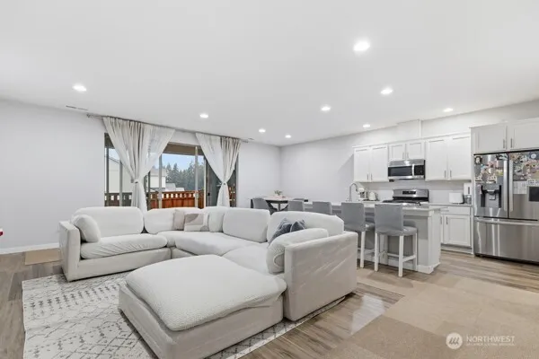 a living room with furniture kitchen area and a wooden floor