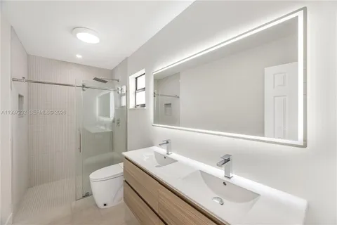 a bathroom with a sink mirror toilet and shower