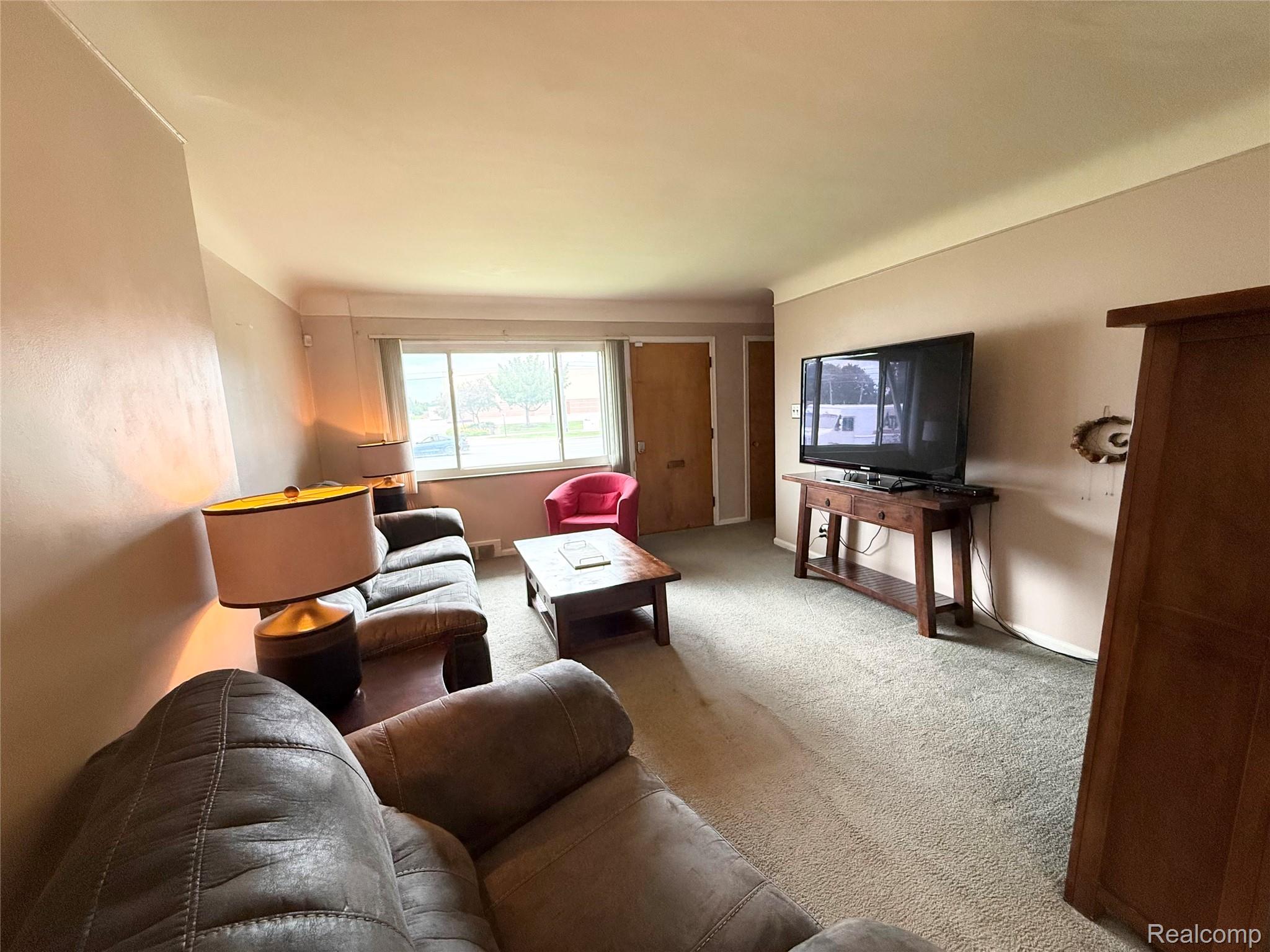 11012 Middlebelt Road Livonia, MI 48150 - Photo 2 of 14 Spacious living area featuring neutral-toned walls, a large window, and carpeted flooring