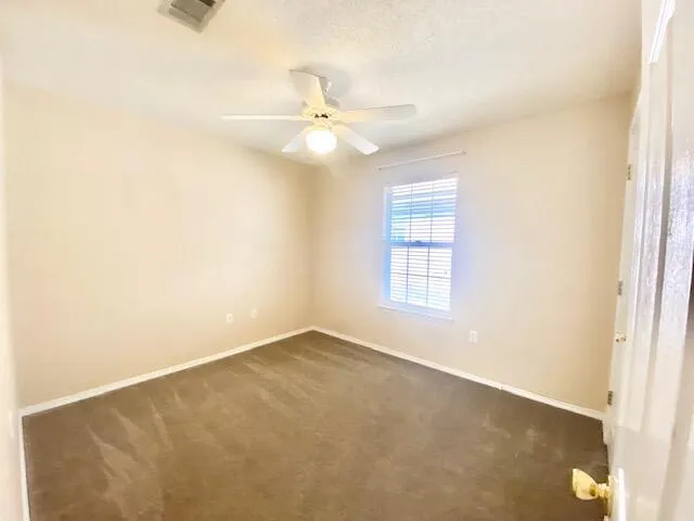 an empty room with a window and a fan