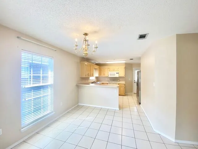 a large white kitchen with a sink and chandelier