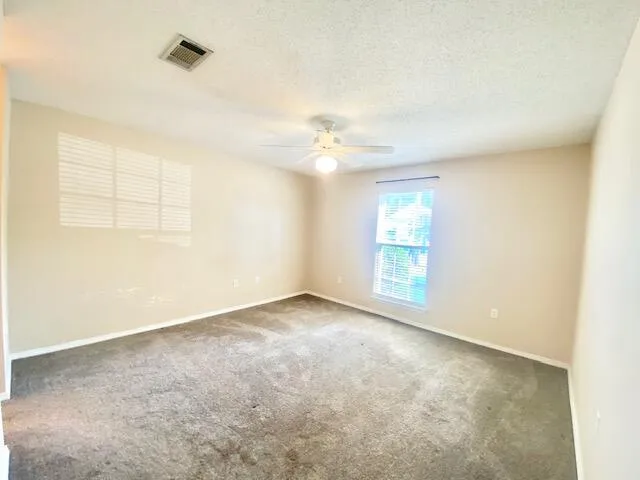 an empty room with windows and fan