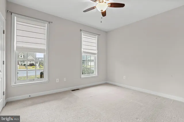 an empty room with windows and fan