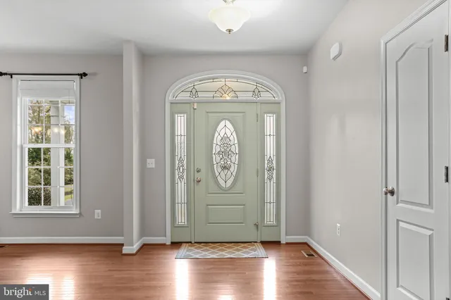 a view of an empty room with wooden floor and kitchen view